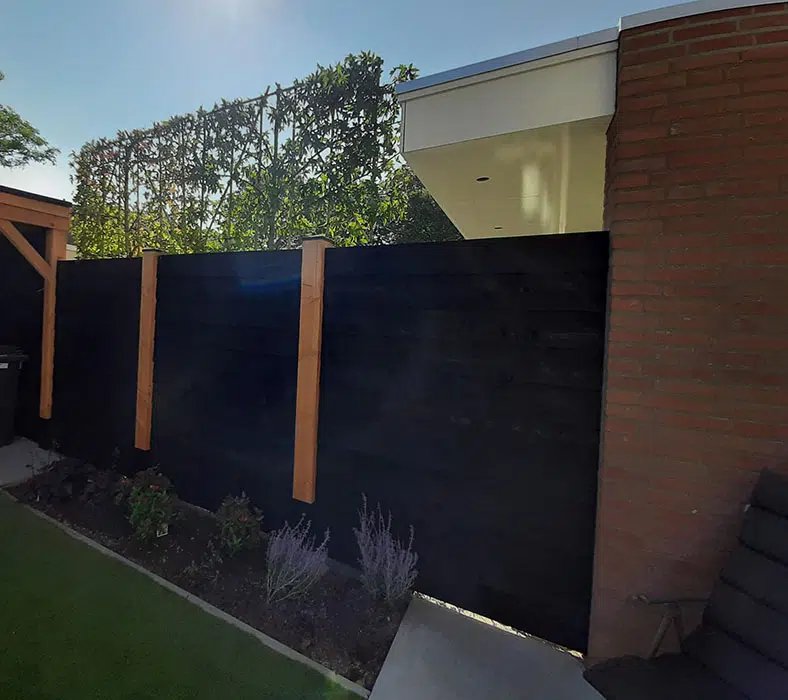 zwart-houten-schutting-tuin Schutting en poort in zelfde stijl als overkapping